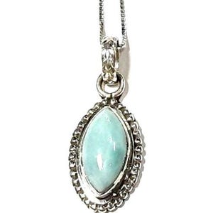 May include: A silver chain necklace with a pendant featuring a light blue oval-shaped gemstone set in a silver bezel with a decorative border.