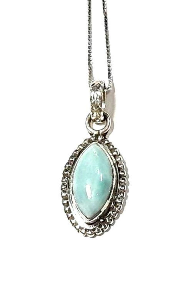 May include: A silver chain necklace with a pendant featuring a light blue oval-shaped gemstone set in a silver bezel with a decorative border.