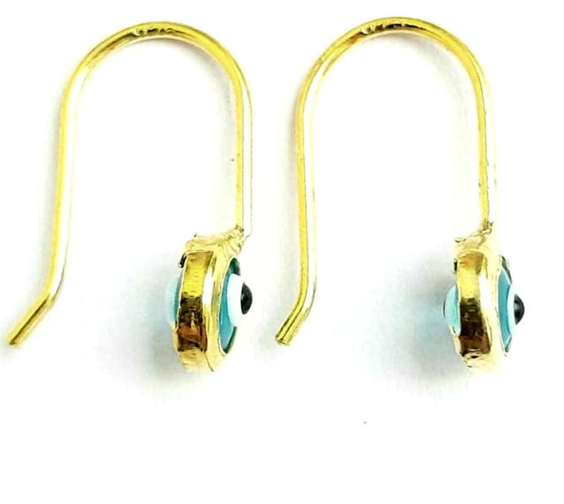 K&ouml;nnte beinhalten: Ein Paar goldene Ohrringe mit einem blauen b&ouml;sen Augen-Anh&auml;nger. Die Ohrringe sind aus Gold und haben einen Hakenverschluss.
