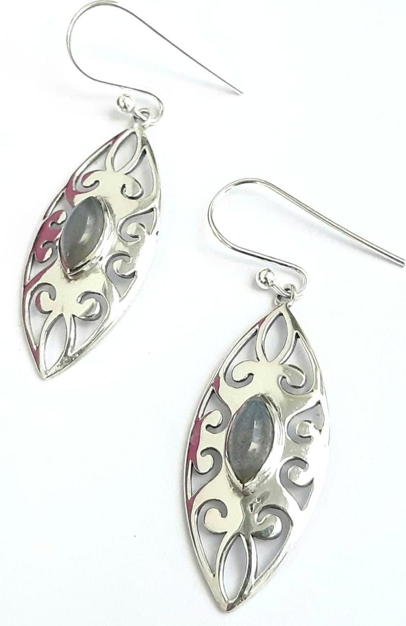 May include: A pair of silver earrings with a delicate filigree design and a gray gemstone in the center of each earring.