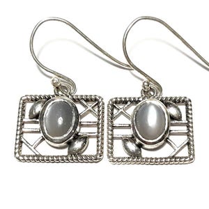 May include: A pair of silver earrings with a gray moonstone in a geometric design.