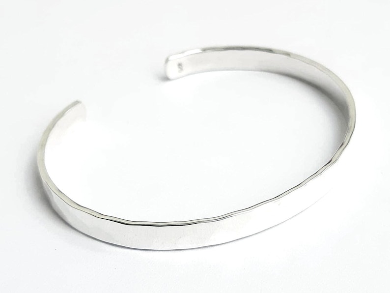 May include: A silver hammered bangle bracelet. The bracelet is simple and elegant, with a smooth, polished finish.
