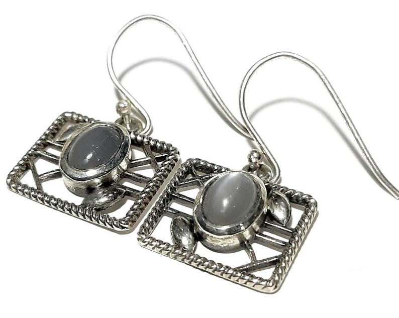 May include: A pair of silver earrings with a gray stone set in a geometric design.
