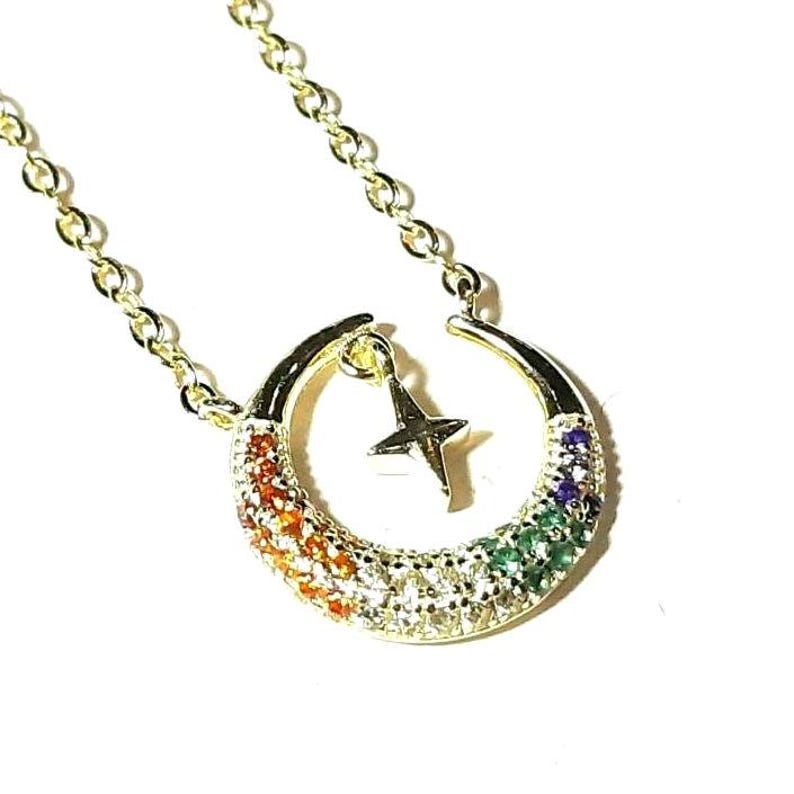 May include: Gold necklace with a crescent moon pendant adorned with colorful gemstones and a small star charm.