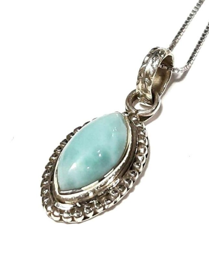May include: A silver pendant necklace with a light blue oval-shaped gemstone set in a silver bezel. The pendant has a detailed silver border.