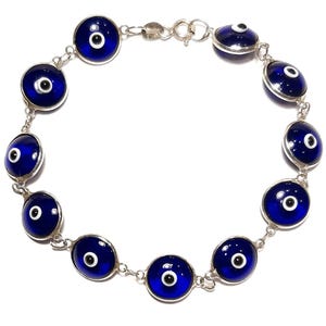 Op de afbeelding: Een zilveren armband met meerdere blauwe boze oog bedels. De bedels zijn rond en hebben een witte kern met een zwarte pupil.