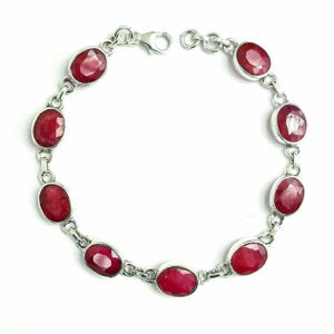 Puede incluir: Un brazalete de plata con piedras preciosas ovaladas rojas. El brazalete tiene un cierre de langosta.