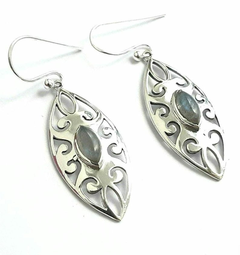 May include: Silver earrings with a delicate filigree design and a light blue gemstone in the center.