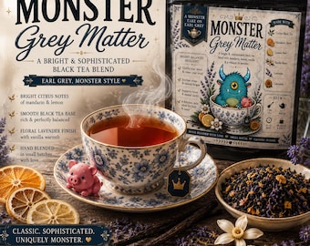 May include: A black tea blend labeled Monster Grey Matter in a pouch next to a floral teacup filled with tea. The pouch features a blue monster illustration and lists ingredients like mandarin, lemon, and lavender. Loose tea sits in a small bowl.