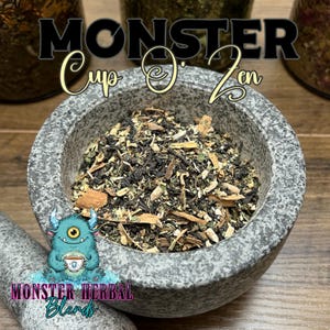 Può includere: Un mortaio di pietra grigia pieno di una miscela di erbe e spezie. Il testo "MONSTER Cup O' Zen" è visualizzato sopra il mortaio. Un mostro dei cartoni animati che tiene una tazza di tè è in basso, con il testo "MONSTER HERBAL Blends".