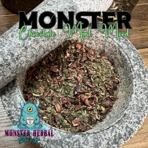 May include: A gray granite mortar and pestle containing a mix of green herbs and brown cocoa nibs. The text "MONSTER Chocolate Mint Mood" is above the mortar. The "MONSTER HERBAL Blends" logo is at the bottom.