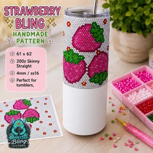 May include: A cylindrical tumbler featuring a partial strawberry pattern created with small, sparkling rhinestones. The upper portion displays pink and green strawberry motifs, while the lower section is plain white. A metal straw is inserted in the lid.