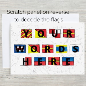 May include: A white card with the words "YOUR WORDS HERE" spelled out using nautical signal flags. Each flag is a different colour, with red, yellow, blue, and black. The flags are on a white background with a map printed behind them. The text "Scratch panel on reverse to decode the flags" is printed at the top of the card.