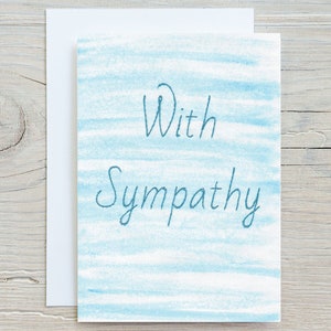 May include: A sympathy card with a blue watercolour background and the text "With Sympathy" in dark blue.