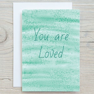 May include: A green watercolour card with the text "You are Loved" written in green.