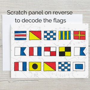 May include: A white card with a grid of 12 colourful nautical flags. The flags are red, yellow, blue, and black. The card has the text "Scratch panel on reverse to decode the flags".