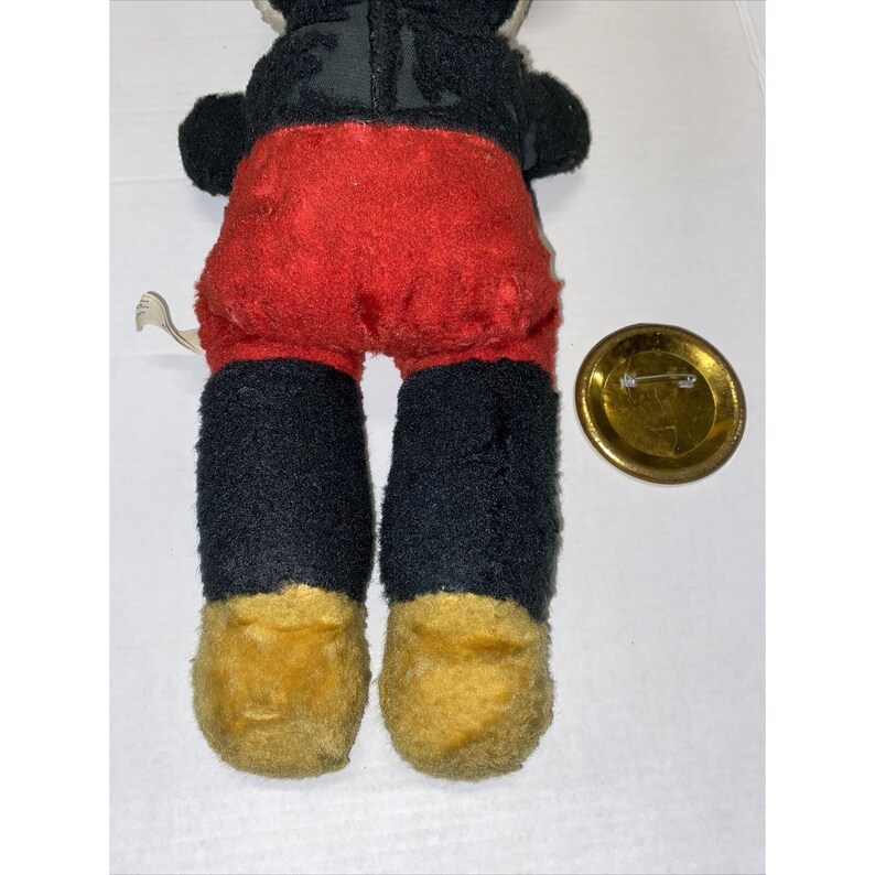 May include: A vintage plush Mickey Mouse toy with black fur, red shorts, and yellow shoes. The toy is in good condition with some wear and tear.