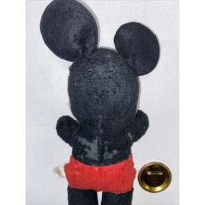 May include: Vintage black and red Mickey Mouse plush toy with a button on the back. The button is gold with a white design.