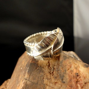May include: A silver ring with a leaf design. The ring is made of sterling silver and has a textured finish.