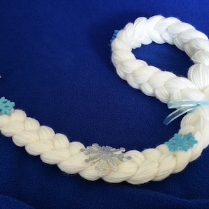 May include: White yarn braid with blue snowflake embellishments. The braid is long and thick, and it is perfect for a costume or cosplay.