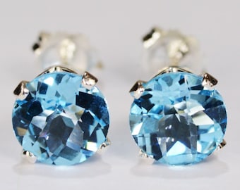 May include: A pair of stud earrings featuring round, faceted, light blue gemstones set in silver-colored metal. The gemstones are the focal point, showcasing their clarity and color. The earrings are designed for pierced ears.