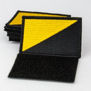 May include: A stack of black and yellow fabric patches with a diagonal line dividing the colors. The patches have a hook and loop fastener on the back.