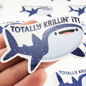 May include: A blue and white whale shark sticker with the text "Totally Krillin' it!" printed on it. The sticker is on a white background.