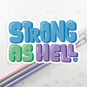 May include: A sticker with the text "Strong as Hell!" in a colorful, cartoon font. The sticker is on a white background with a light blue pattern.