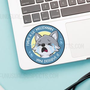 K&ouml;nnte beinhalten: Ein runder Aufkleber in Blau und Gelb mit einem weinenden Cartoon-Wolf. Der Aufkleber sagt "Have a lil' meltdown you deserve it".