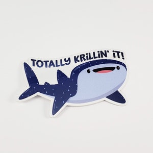 May include: A blue and white whale shark sticker with the text "Totally Krillin' It!" The whale shark has a smiling face and black spots.