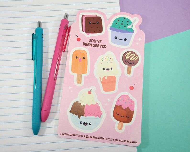 May include: A pink sticker sheet featuring various ice cream designs with smiling faces. The sheet includes ice cream sandwiches, sundaes, and popsicles. The text "YOU'VE BEEN SERVED" is printed on the sheet. Two pens, one teal and one pink, are on the left.