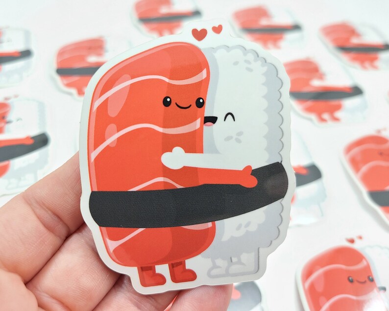 Puede incluir: Una pegatina de dos rollos de sushi abraz&aacute;ndose. El rollo de salm&oacute;n es rojo con una envoltura de alga negra y el rollo de arroz blanco tiene una envoltura de alga negra. Ambos rollos tienen caras lindas y sostienen corazones.