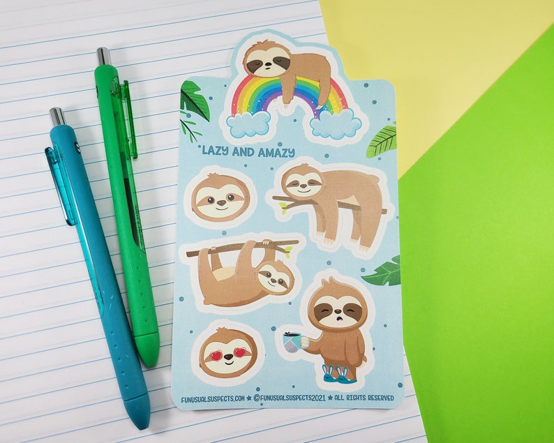 Pode incluir: Uma folha de adesivos de pregui&ccedil;a coloridos com um arco-&iacute;ris e nuvens. Os adesivos dizem "Lazy and Amazay".
