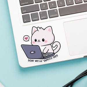 K&ouml;nnte beinhalten: Eine wei&szlig;e Katze mit rosa Wangen sitzt an einem Laptop mit dem Text "DOIN' MY LIL' TAPPITY TAPS" am unteren Rand des Bildes.