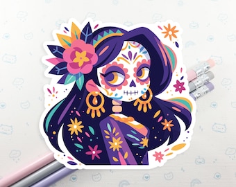 Puede incluir: Una pegatina colorida con una ilustración inspirada en el Día de Muertos de una mujer con una cara de calavera de azúcar, cabello negro largo adornado con flores y un vestido con estampado morado y azul.