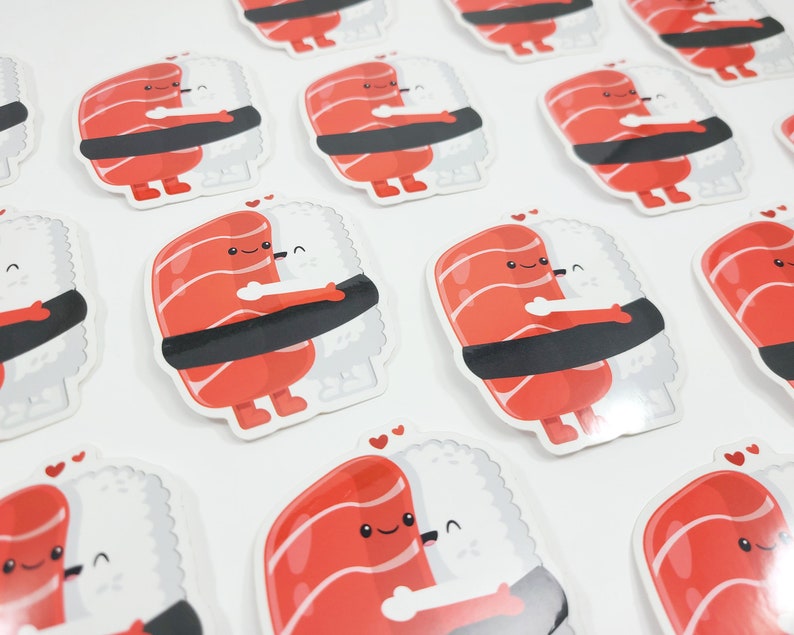 Puede incluir: Un conjunto de 10 pegatinas de sushi lindas con un rollo de sushi rojo y blanco con una cara sonriente abrazando una bola de arroz blanca con una cara sonriente. Las pegatinas son perfectas para agregar un toque de diversi&oacute;n a las computadoras port&aacute;tiles, botellas de agua, diarios y m&aacute;s.