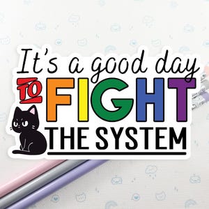 May include: A sticker with a black cat and the text "It's a good day to FIGHT THE SYSTEM" in rainbow colors.