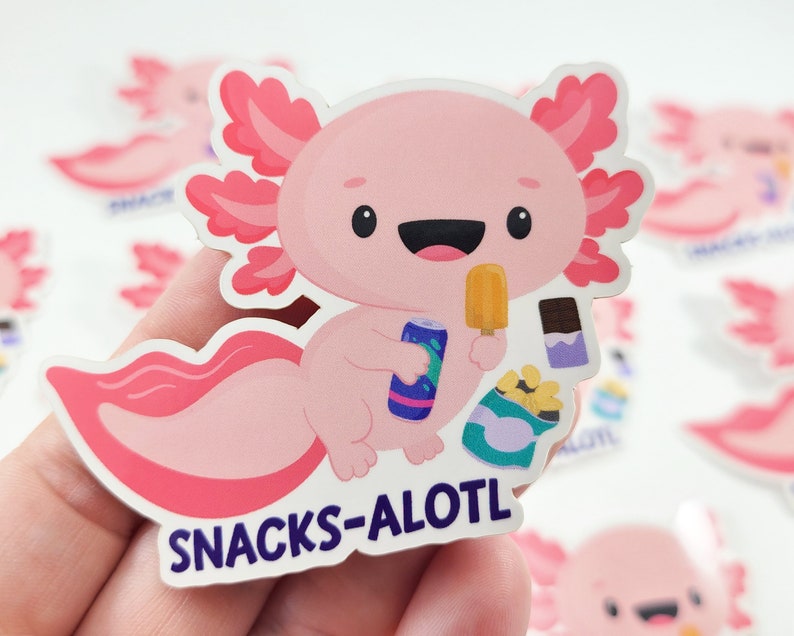 Puede incluir: Una pegatina de dibujos animados de axolotl rosa con una expresi&oacute;n feliz, sosteniendo una paleta de hielo y una lata de refresco. El axolotl lleva una camisa a rayas azul y blanca y tiene una cola rosa. La pegatina dice "SNACKS-ALOTL" en letras moradas.