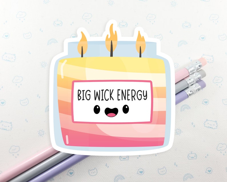Może przedstawiać: Naklejka z kresk&oacute;wkową świecą z uśmiechającą się twarzą i tekstem "BIG WICK ENERGY". Świeca jest ż&oacute;łta, pomarańczowa i r&oacute;żowa z niebieskim wieczkiem.