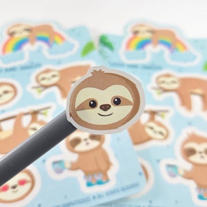Pode incluir: Uma folha de adesivos coloridos com ador&aacute;veis ​​bichos-pregui&ccedil;a de desenho animado em v&aacute;rias poses. Os bichos-pregui&ccedil;a s&atilde;o marrons com olhos grandes e sorrisos. Alguns bichos-pregui&ccedil;a est&atilde;o segurando x&iacute;caras de caf&eacute;, enquanto outros est&atilde;o pendurados nos galhos. Os adesivos s&atilde;o perfeitos para adicionar um toque de fantasia ao seu planejador, laptop ou garrafa de &aacute;gua.