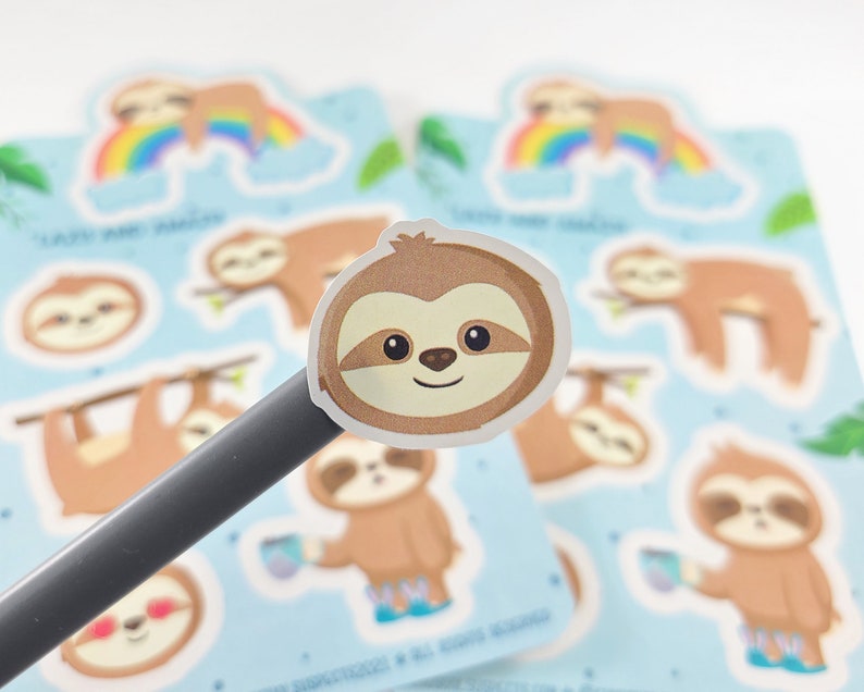 Pode incluir: Uma folha de adesivos coloridos com ador&aacute;veis ​​bichos-pregui&ccedil;a de desenho animado em v&aacute;rias poses. Os bichos-pregui&ccedil;a s&atilde;o marrons com olhos grandes e sorrisos. Alguns bichos-pregui&ccedil;a est&atilde;o segurando x&iacute;caras de caf&eacute;, enquanto outros est&atilde;o pendurados nos galhos. Os adesivos s&atilde;o perfeitos para adicionar um toque de fantasia ao seu planejador, laptop ou garrafa de &aacute;gua.