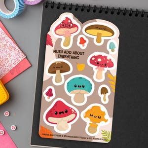 May include: A sheet of colorful mushroom stickers with cute faces. The stickers feature different colors and designs, including red, brown, blue, and yellow. The text "Mush Ado About Everything" is printed on the sheet.