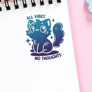 Puede incluir: Una pegatina con una ilustraci&oacute;n de un gato degradado en azul y morado. El gato tiene ojos grandes y una cola esponjosa. El texto "ALL VIBES NO THOUGHTS" est&aacute; debajo del gato.
