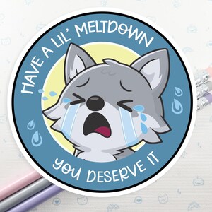 K&ouml;nnte beinhalten: Ein blauer und wei&szlig;er Aufkleber mit einem weinenden Cartoon-Wolf. Der Text auf dem Aufkleber lautet "Have a lil' meltdown you deserve it."