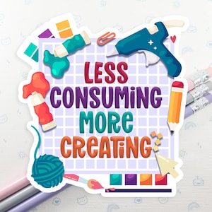 May include: A colorful sticker with the text "LESS CONSUMING MORE CREATING" surrounded by art supplies. Includes a glue gun, paint tubes, pencils, and a ball of yarn. The sticker is on a white background with a repeating pattern of clouds and cat faces.