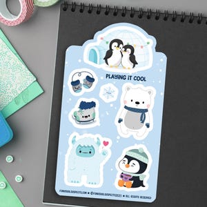 Puede incluir: Un conjunto de seis pegatinas de tem&aacute;tica invernal con un oso polar, ping&uuml;inos, un yeti, guantes y patines. Las pegatinas est&aacute;n sobre un fondo azul con el texto "Playing it Cool".