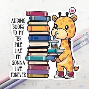 May include: A sticker featuring a cartoon giraffe with a stack of books and a coffee cup. The giraffe is holding more books and has a heart above its head. Text on the left reads: "Adding books to my TBR pile like I'm gonna live forever."