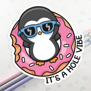 May include: A sticker featuring a cartoon penguin wearing sunglasses and floating in a pink doughnut with white sprinkles. The text "It's a hole vibe" is written around the doughnut.