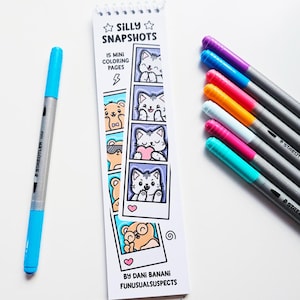 May include: A collection of colorful art supplies, including a blue and silver Staedtler dual-tip marker and several colored Staedtler pens. A small spiral-bound coloring book titled "Silly Snapshots" features cartoon animal illustrations.
