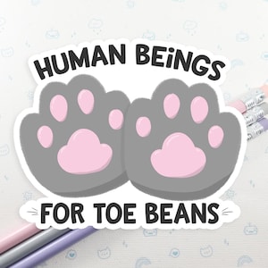 May include: A grey paw print sticker with pink toe beans and the text "HUMAN BEINGS FOR TOE BEANS".